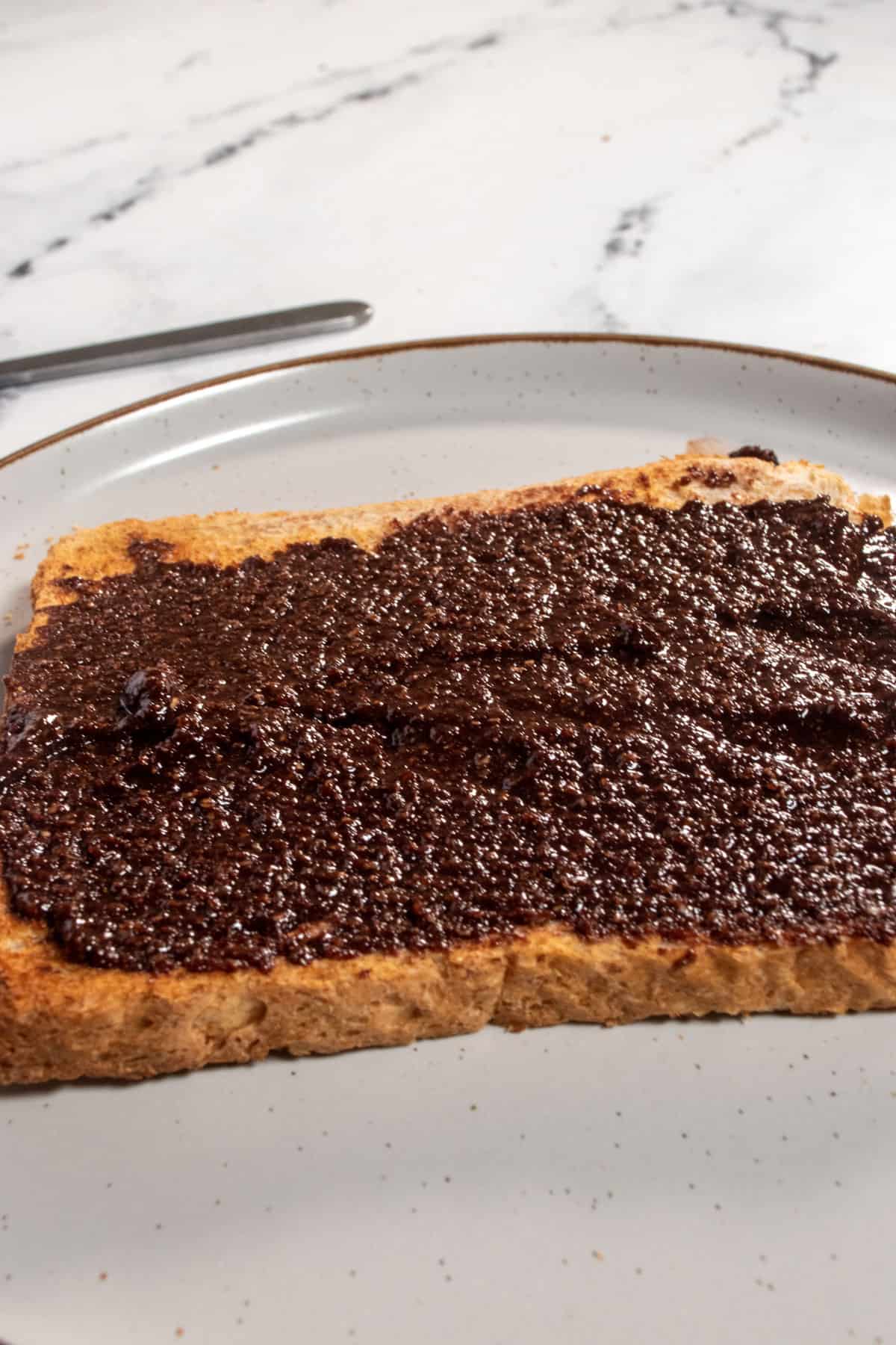 Edible vegan brownie batter spread neatly onto a slice of toast smoothly.