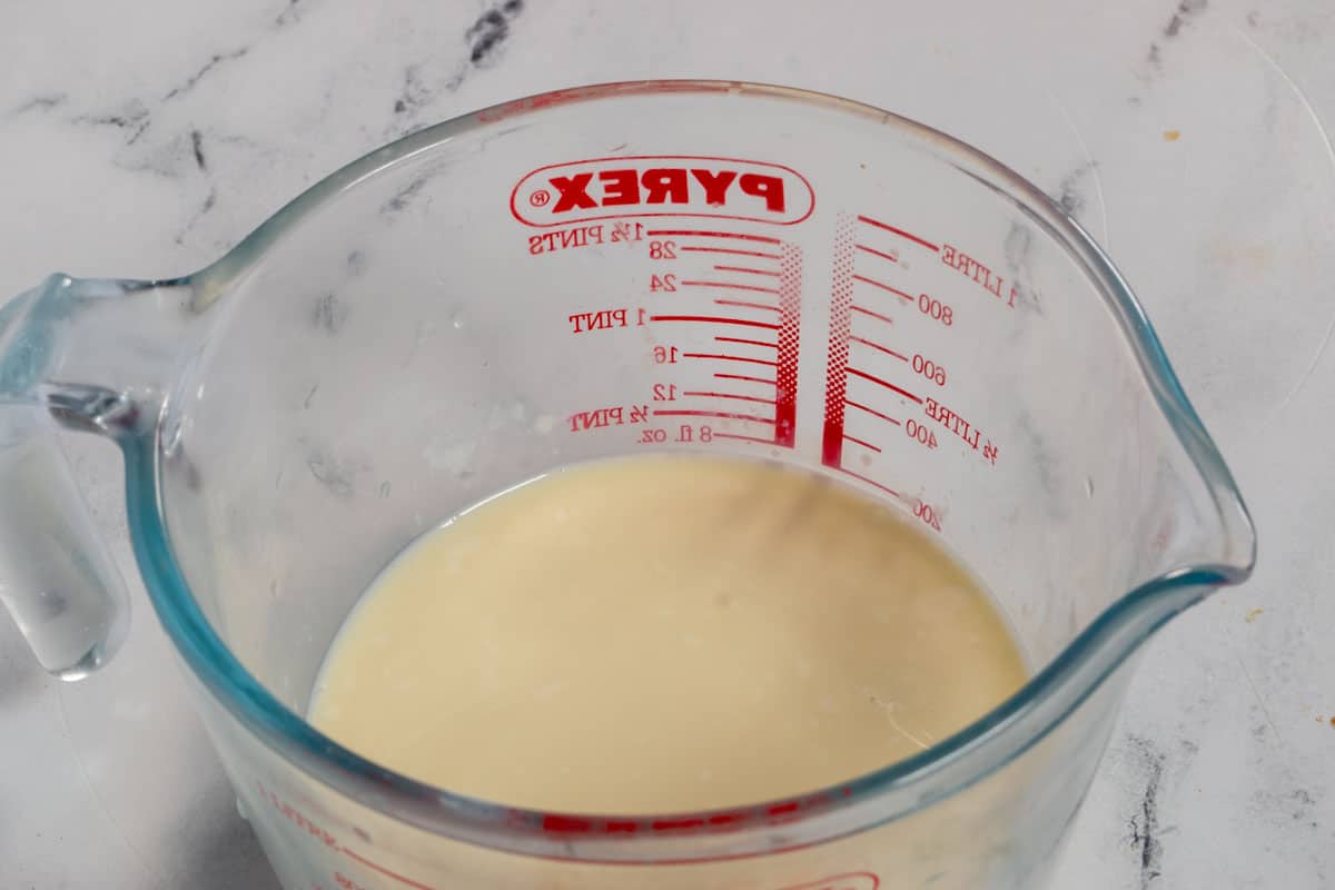 The soy milk and apple cider vinegar mixed together inside a small glass jug.