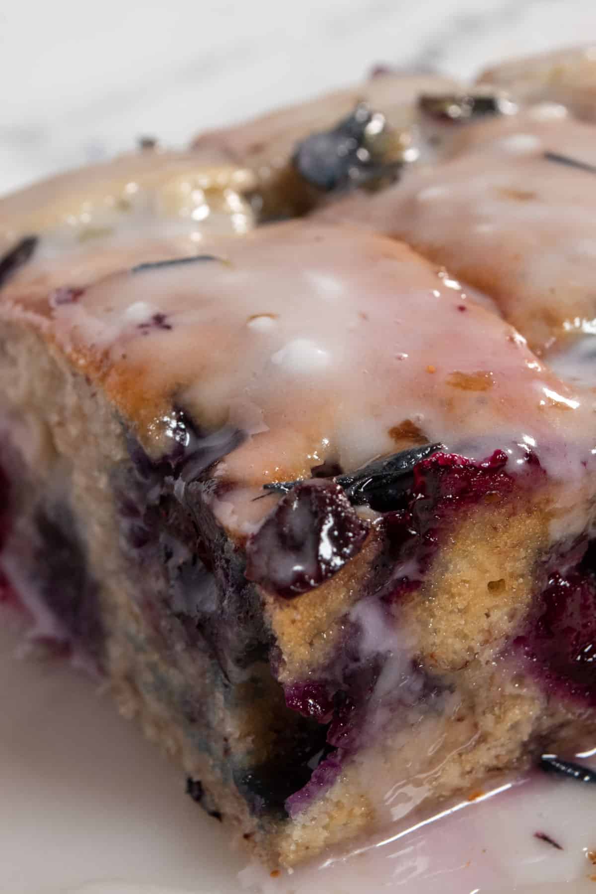 A side angled picture of my vegan blueberry banana cake. Blueberry glaze is dripping down the side.