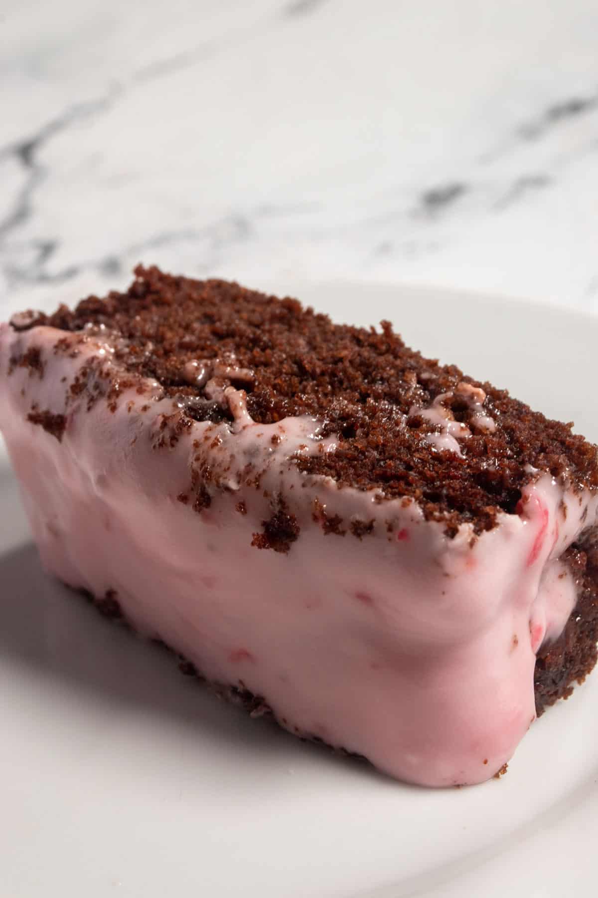 A thick slice of vegan chocolate raspberry cake laying on its side. The crumb of the cake looks moist and fluffy. 