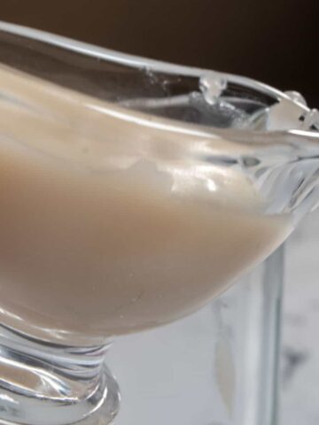 Vegan condensed milk inside glass a pouring jug. It is thick and creamy.