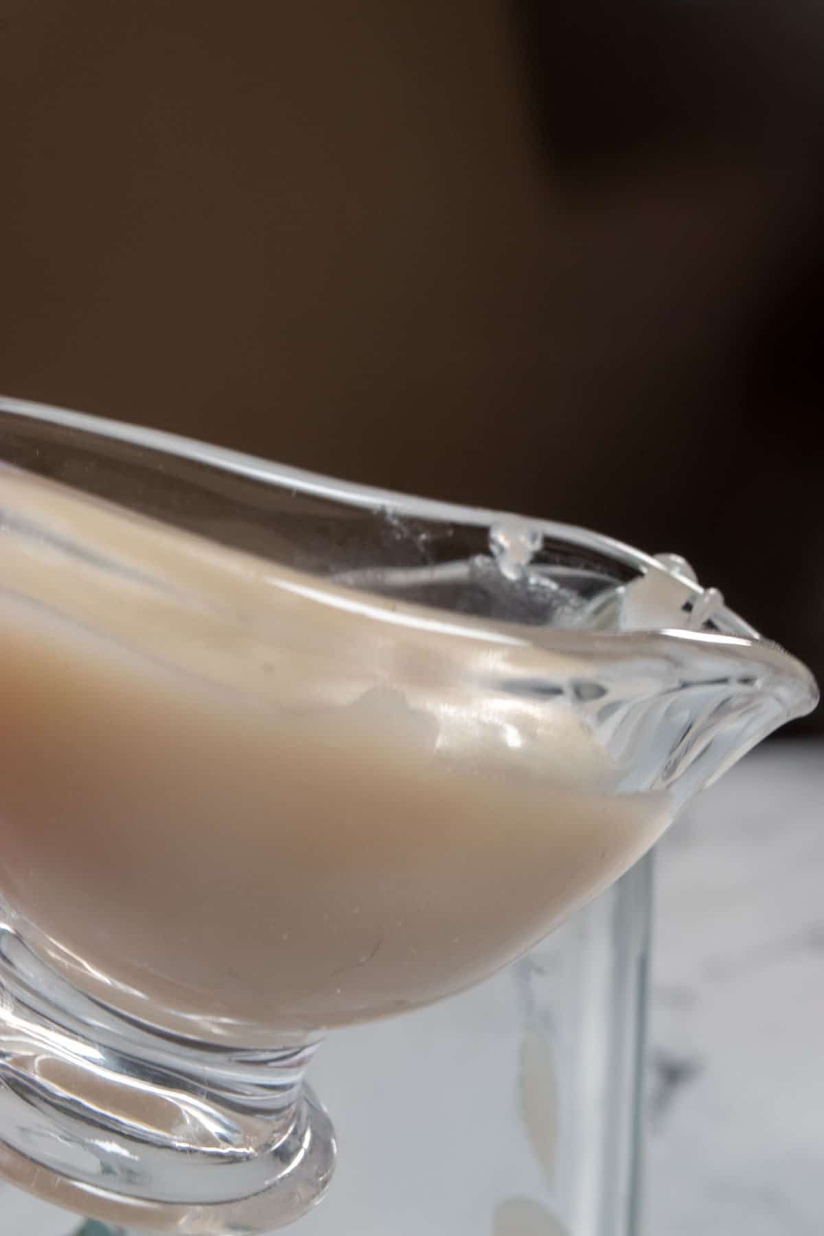 A glass serving jug which is about to pour sweet condensed milk out from the spout. 