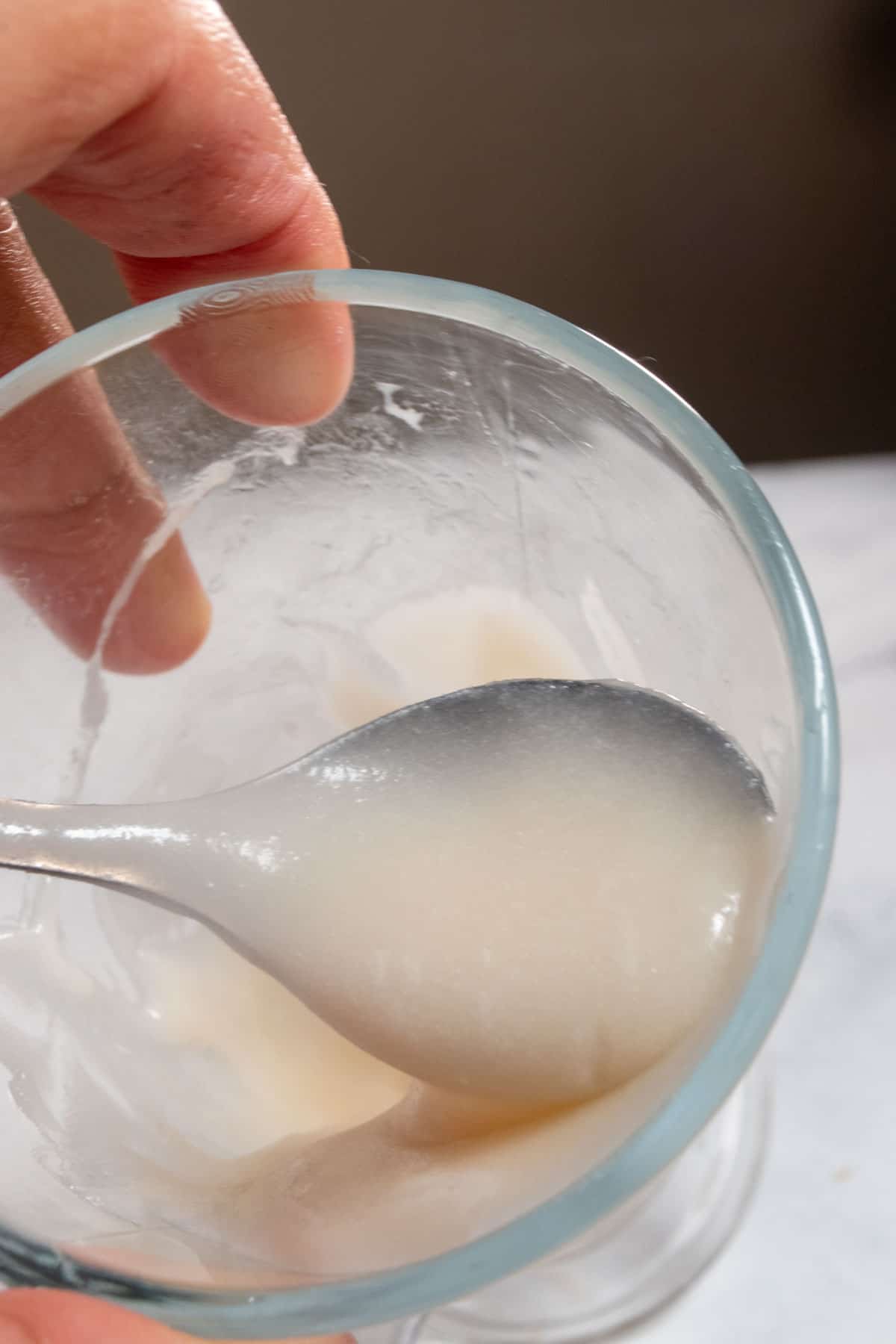 A spoonful of condensed milk inside a glass.