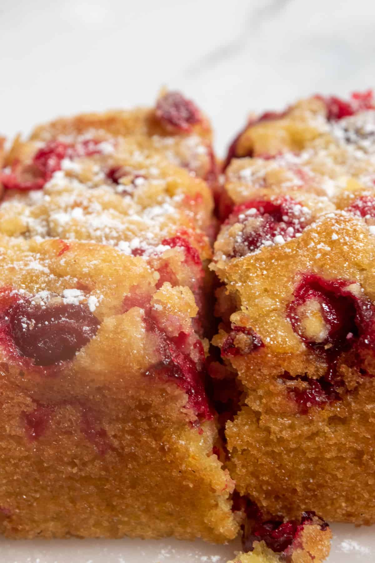 A zoomed in shot of my vegan cranberry orange cake showing the golden brown edges and bright cranberries. 