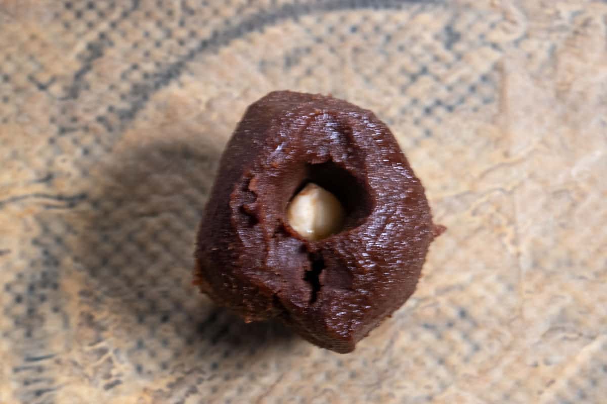 The firm chocolate has been moulded  in a ball. A hazelnut kernel has been pressed into the centre.