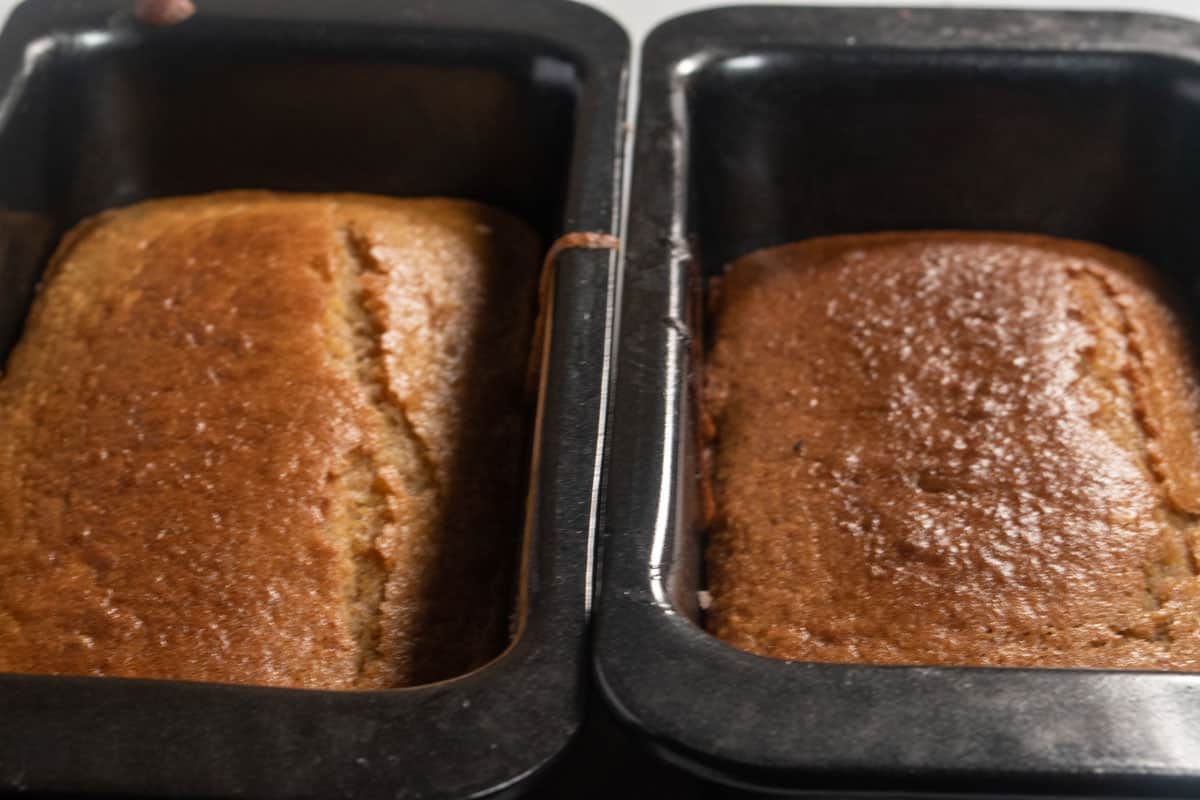 Two baked vegan ginger cakes cooling inside their tins.