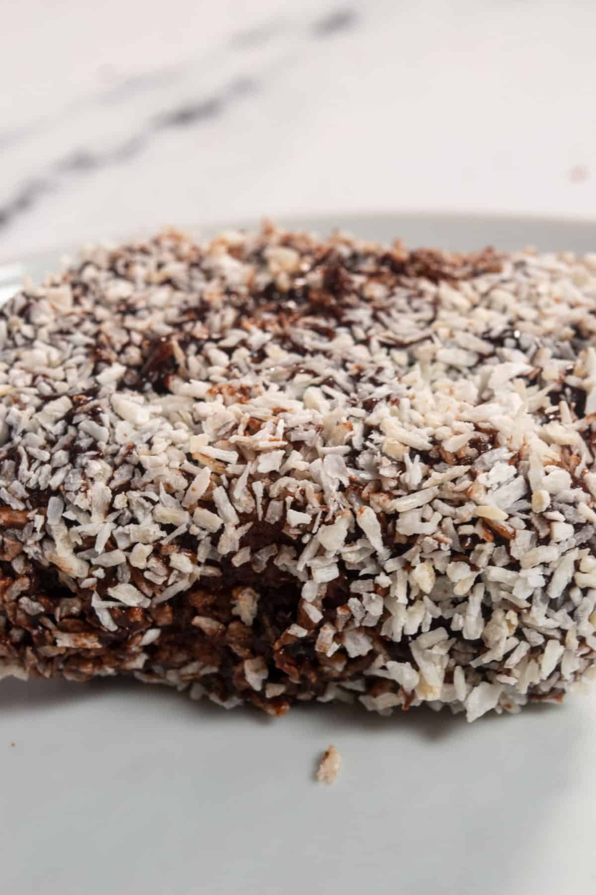 A whole lamington bar covered in lots of coconut and chocolate.