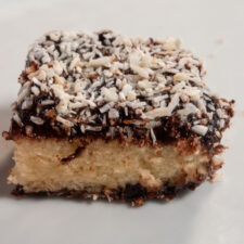 A single slice of vegan lamington cake. It has been sliced open and coconut has been sprinkled on top generously.