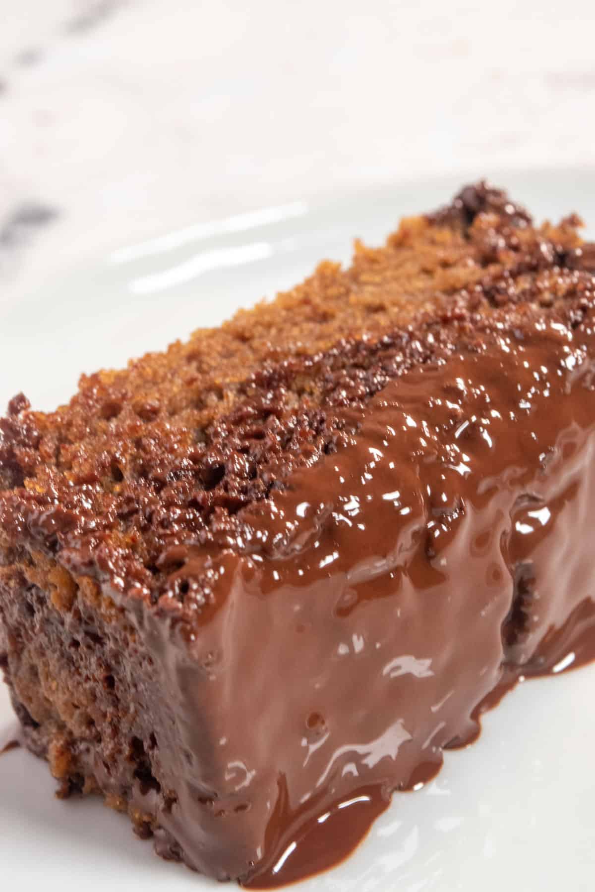 A slice of vegan mocha cake on its side. The glaze has soaked into the cake. 