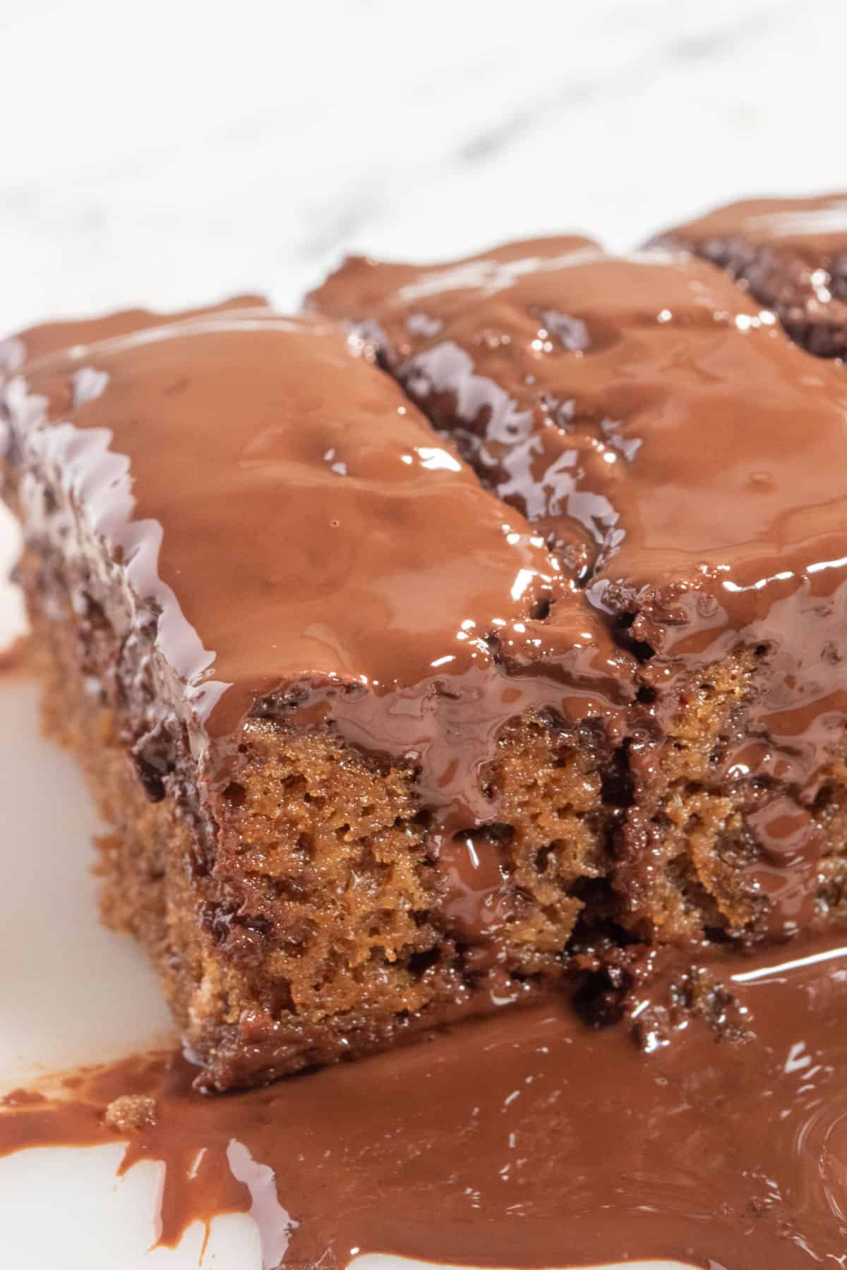 A whole loaf of my vegan mocha cake covered with melted chocolate on a white background.