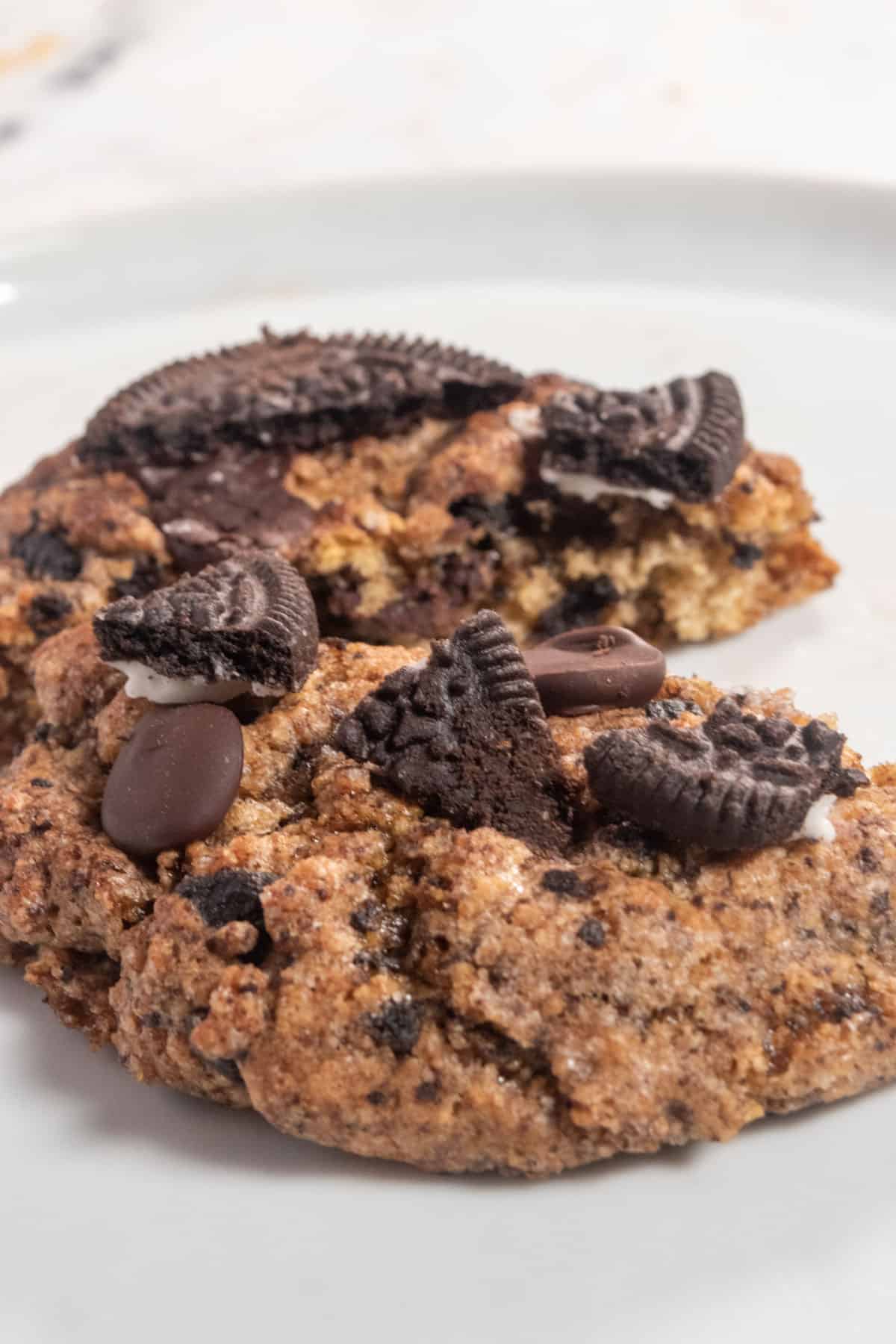 Two vegan oreo cookies on a plate. One us sliced in half. 