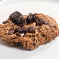 A single vegan oreo cookie on a shiny white plate. Extra oreos have been added on top.