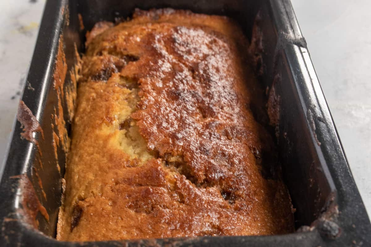 A baked snickerdoodle loaf cake inside its tin cooling down. 