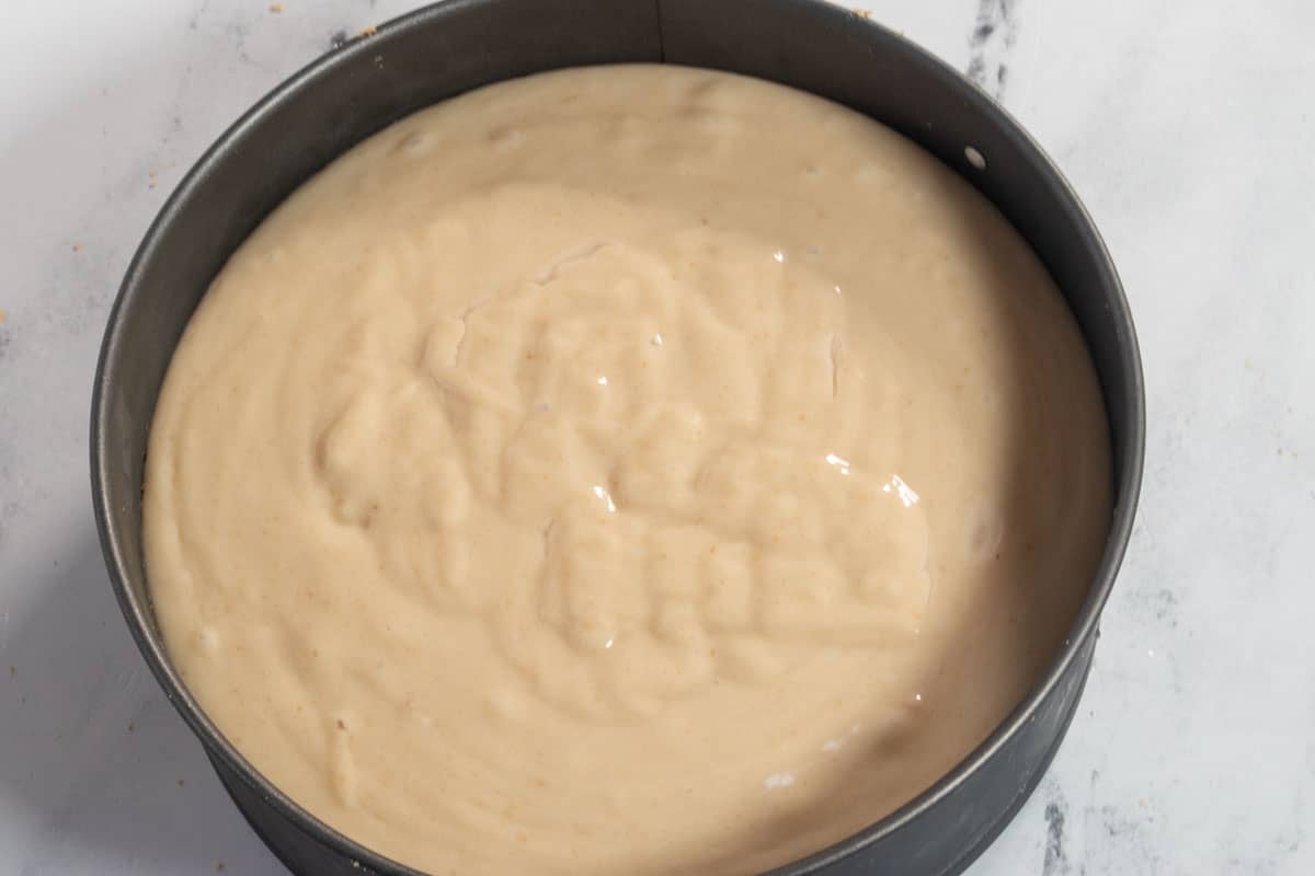 The filling has been poured over the base inside the cheesecake tin. 