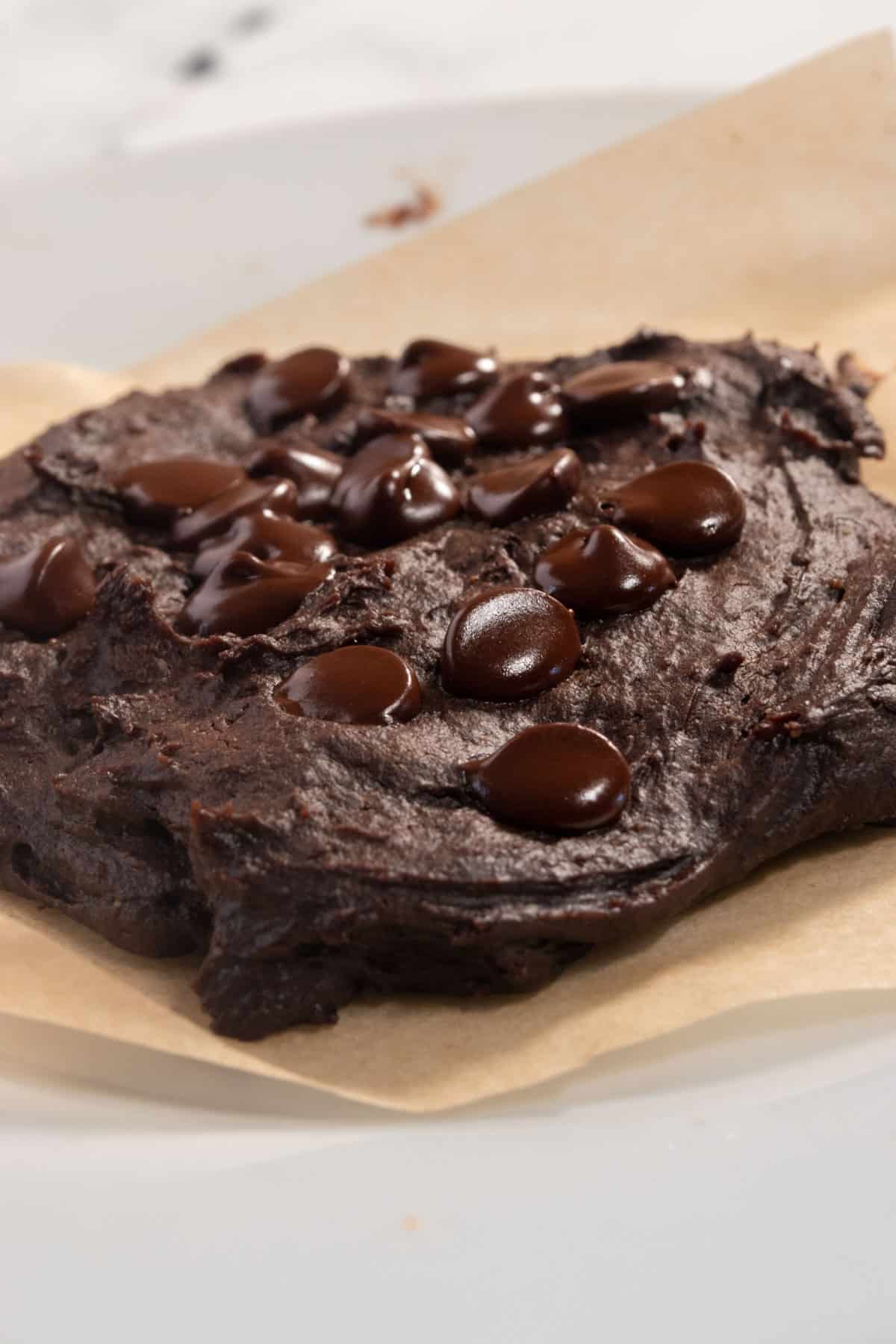 A chocolate cookie on a white plate ready to be eaten. It is shining in the light.