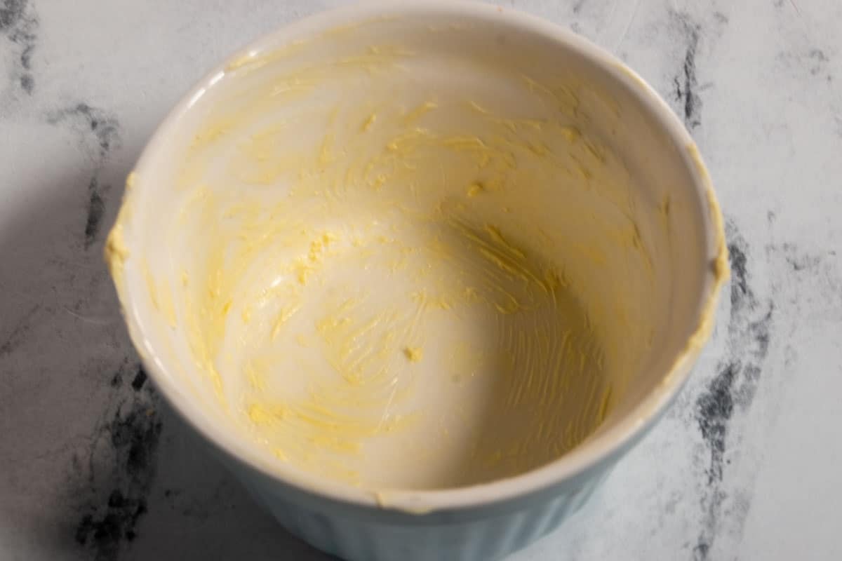 A blue ramekin greased with vegan butter.