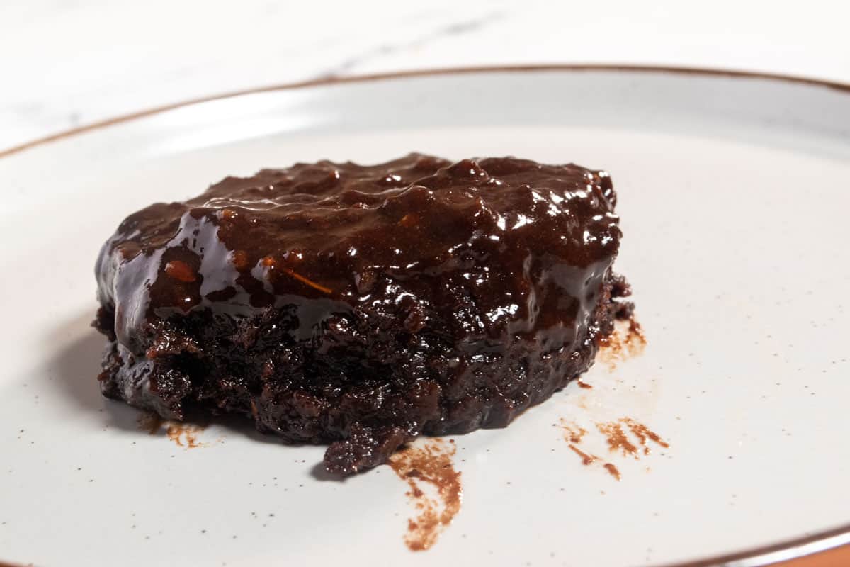 The cooked mug cake is cooling on a brown-rimmed plate. 