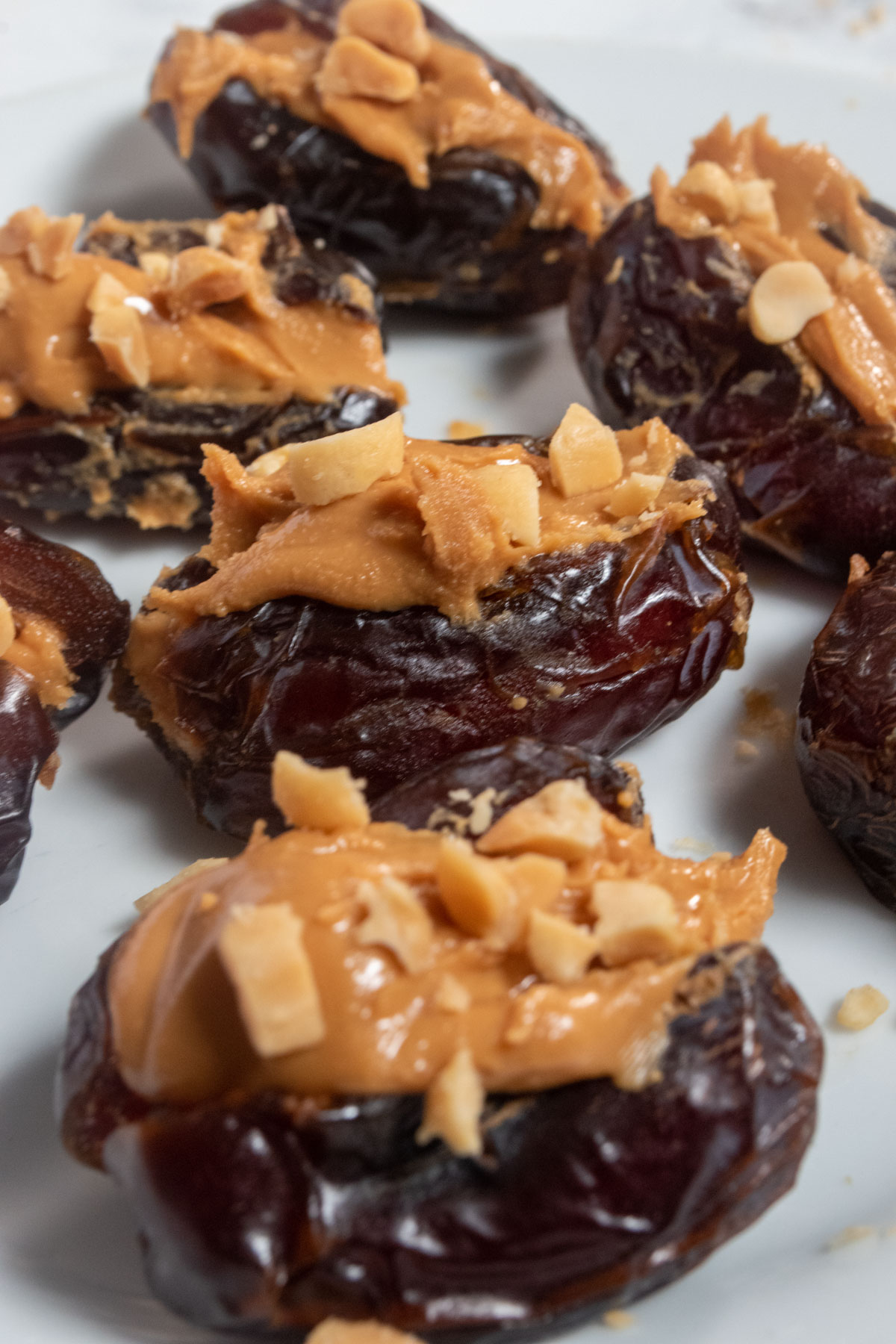 Seven peanut butter stuffed dates without a chocolate topping waiting for some chocolate drizzle. 