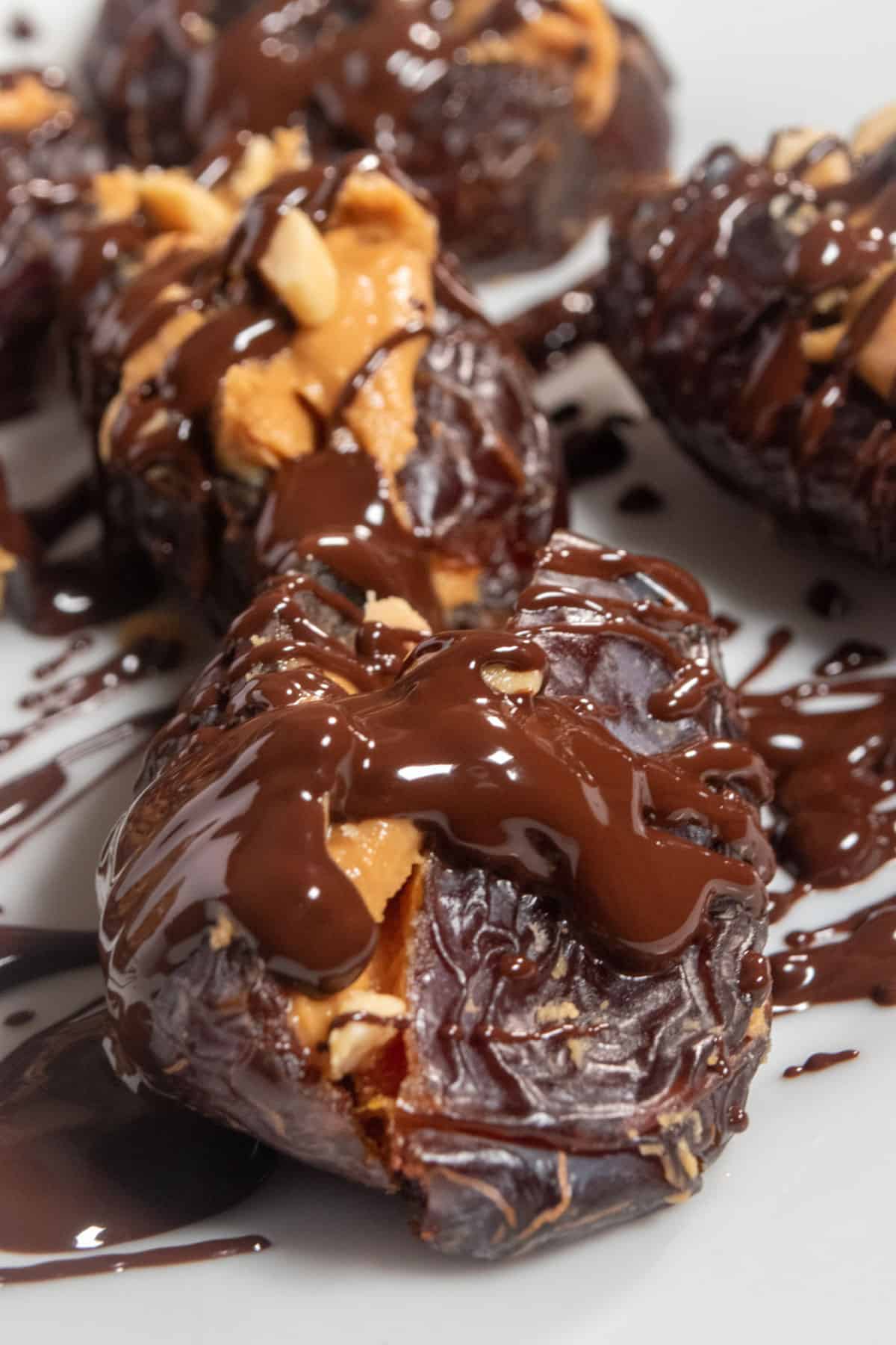 Several chocolate drizzled dates. It looks a little messy as there is a lot of chocolate dripping down the sides of the dates but they also look very delicious.