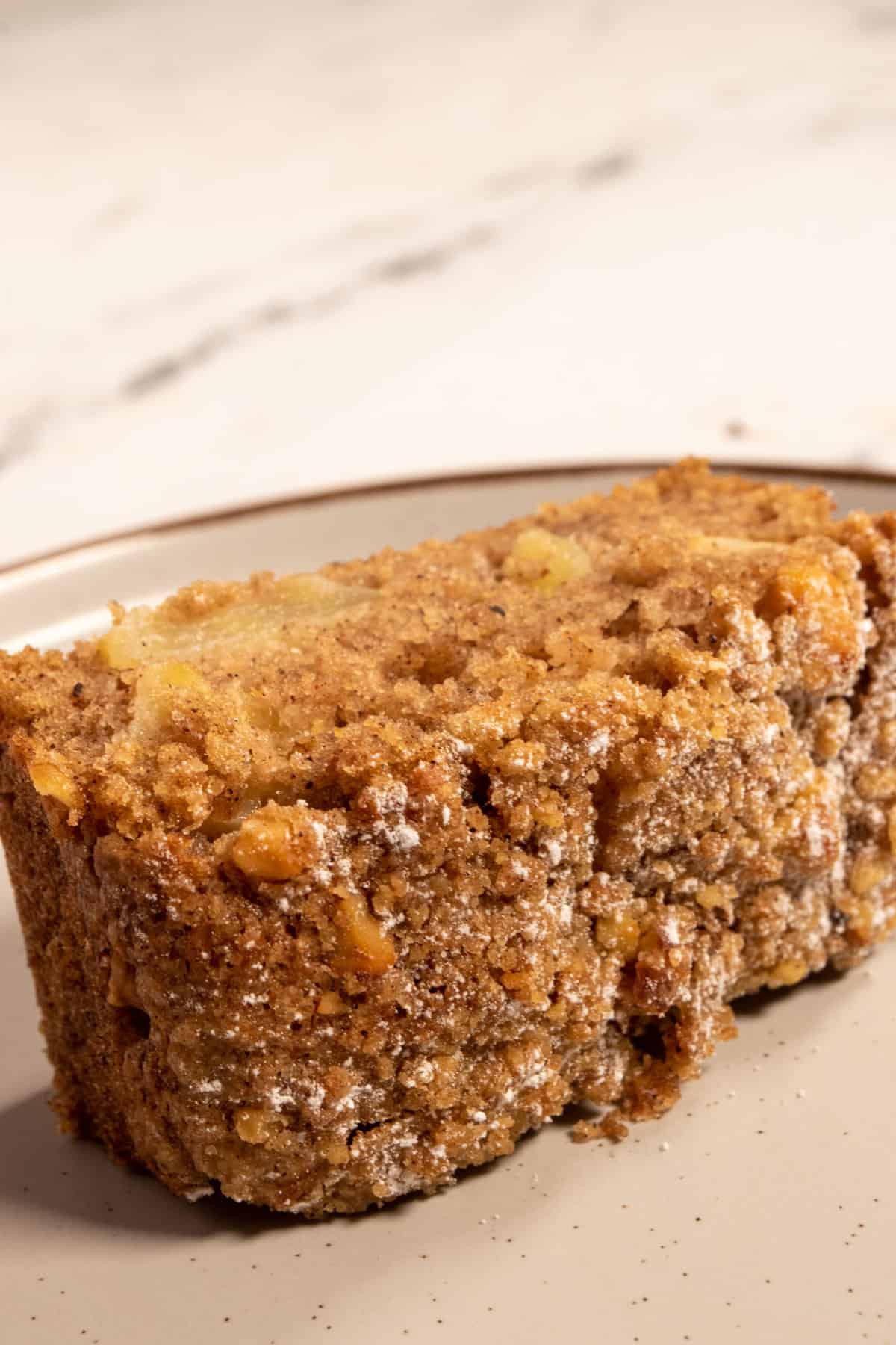 A thick slice of cake with powdered sugar added to the top of the toasty crumble topping. 