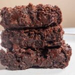 Three fudgy vegan banana brownies stacked on top of each other.