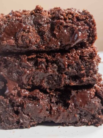 Three fudgy vegan banana brownies stacked on top of each other.