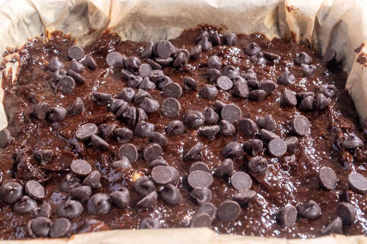 The brownie batter has been poured into the prepared tin. Extra chocolate chips sprinkled on top. 