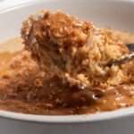 Vegan Biscoff baked oats being lifted towards the camera with a large spoon.