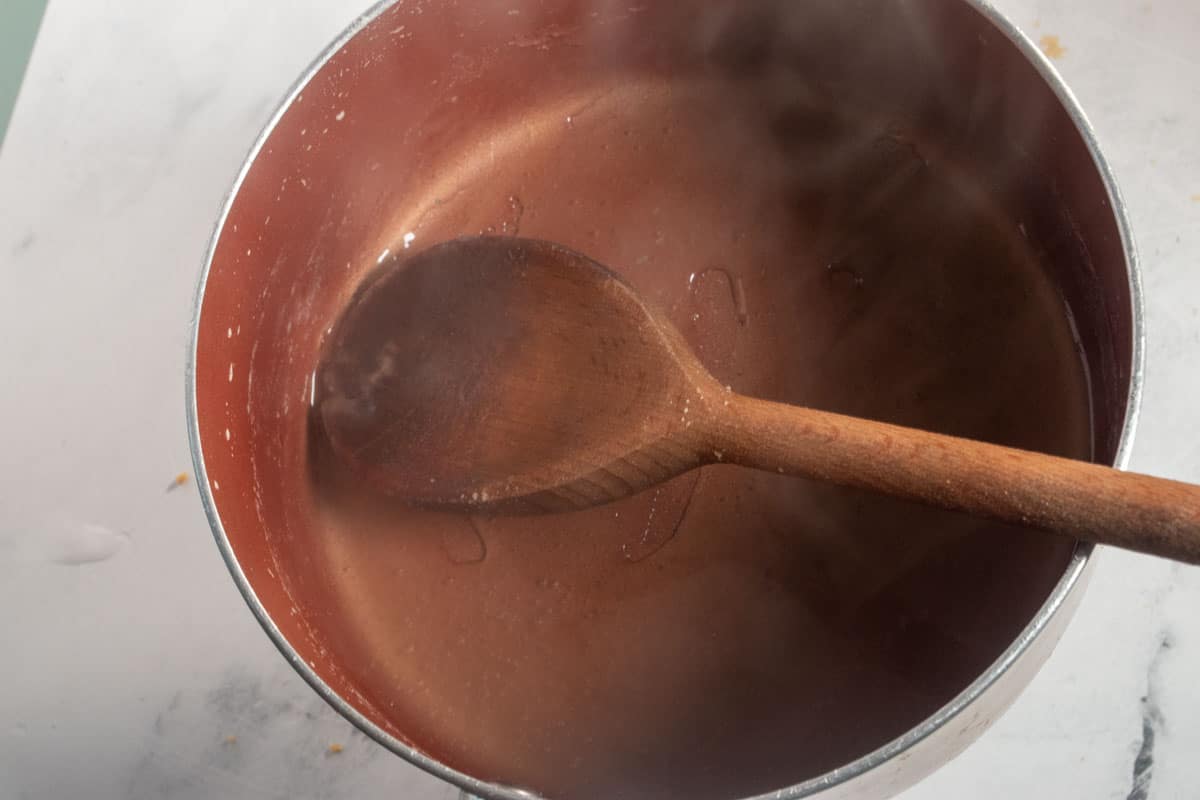 The agar mixture cooking and thickening inside a saucepan. 