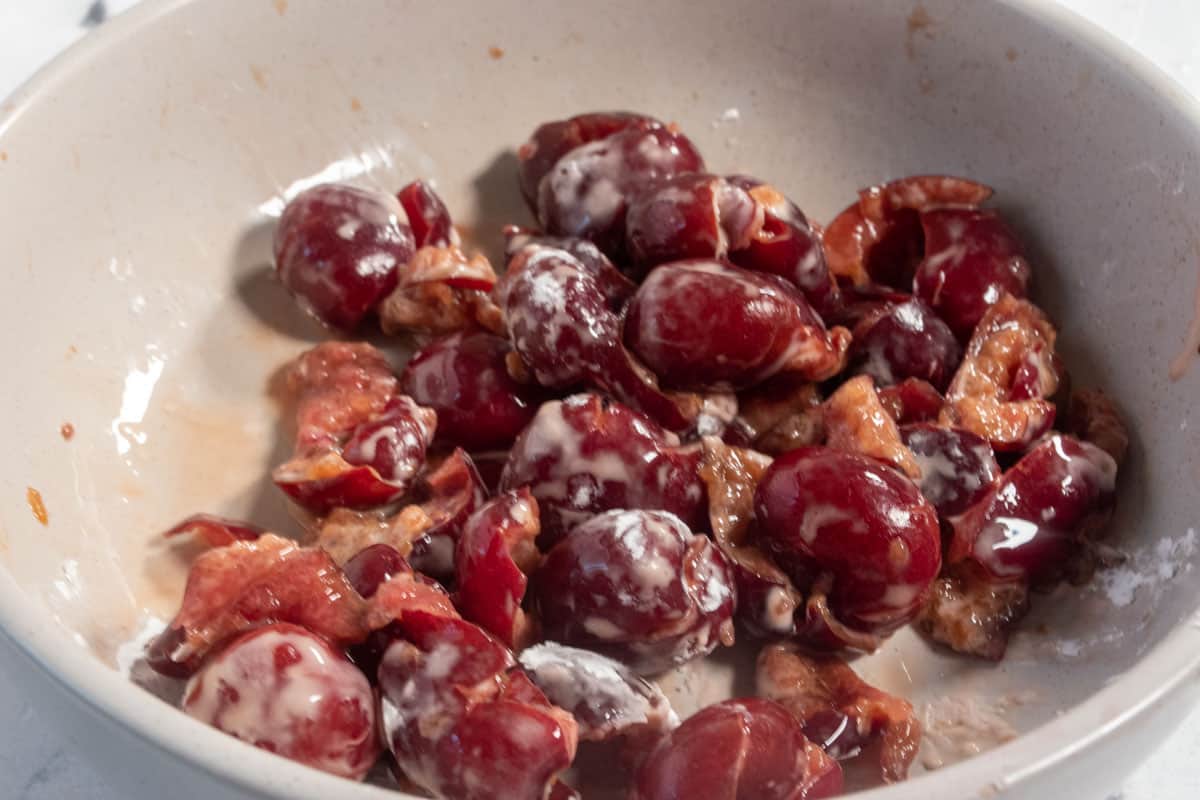 Cherries dusted with cornstarch inside a small, grey bowl.