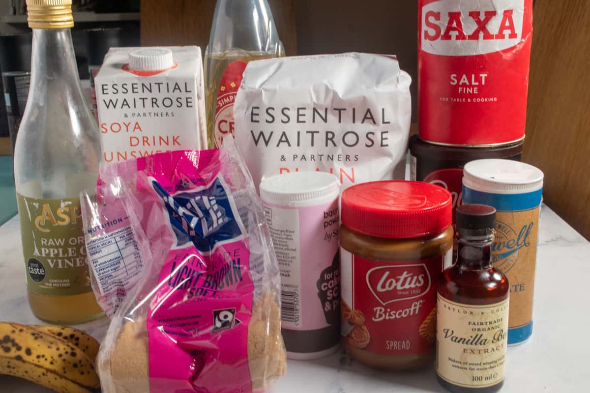 The ingredients needed to make my vegan chocolate banana breads standing on a white marble backdrop. 