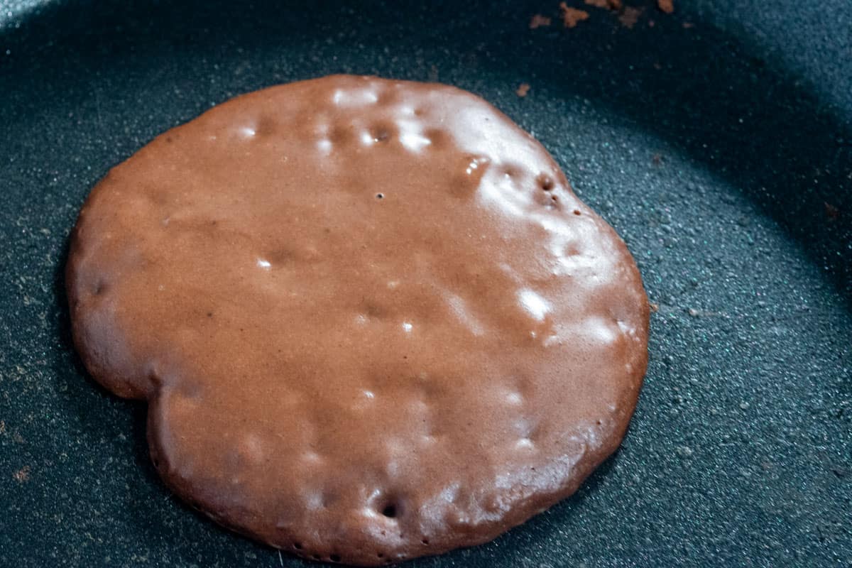 A chocolate pancake frying in the pan. 