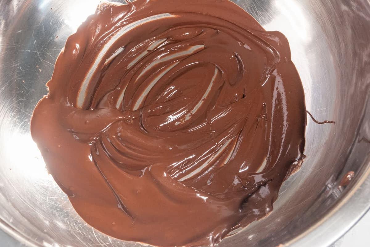 Melted vegan chocolate inside a metal mixing bowl, ready to be poured over the pancakes.