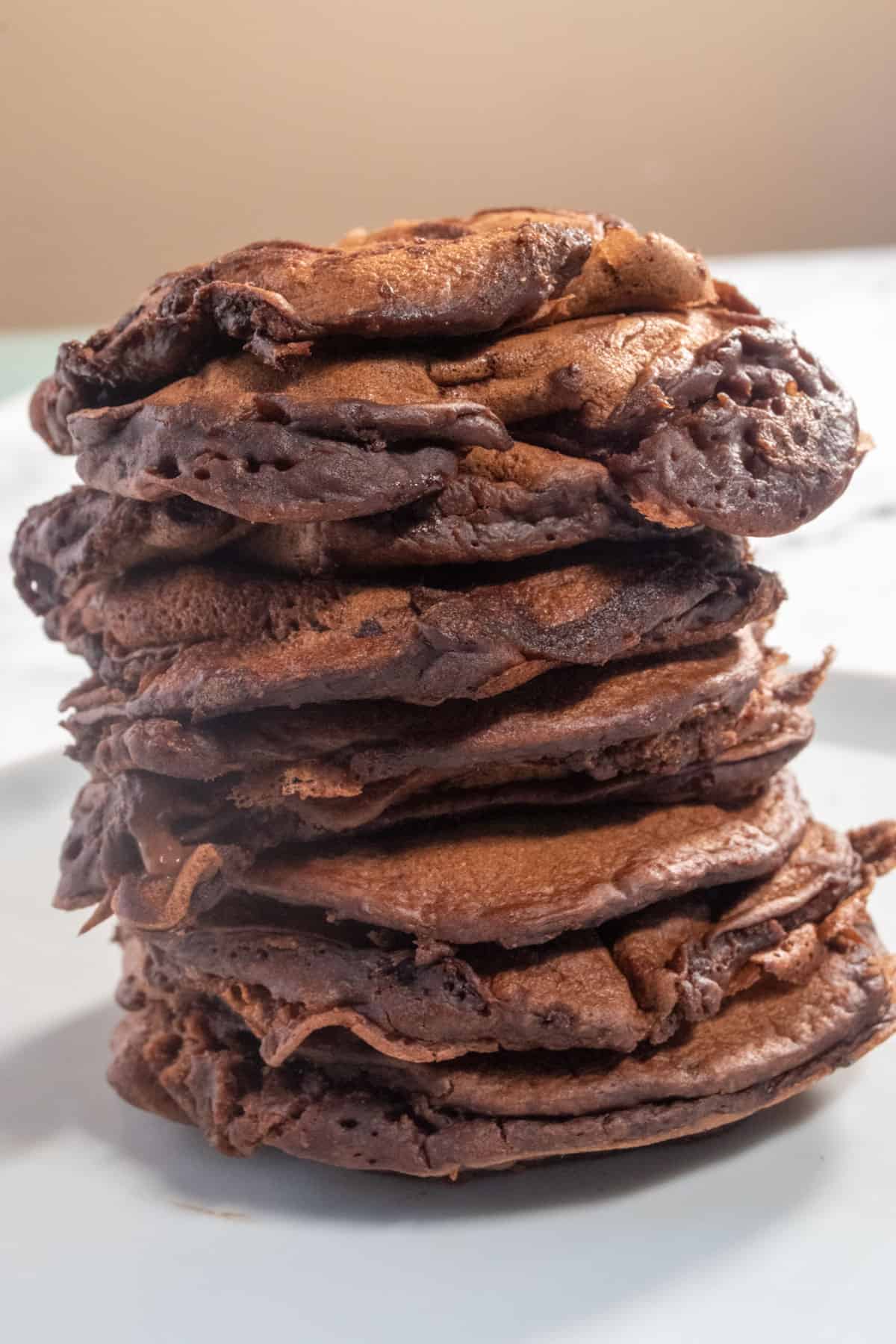 Another stack of vegan chocolate chip pancakes on a white plate. These ones are plain. 