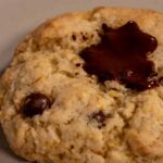 A close up shot of one of my vegan lemon cookies on a white plate. It has melted chocolate on top.