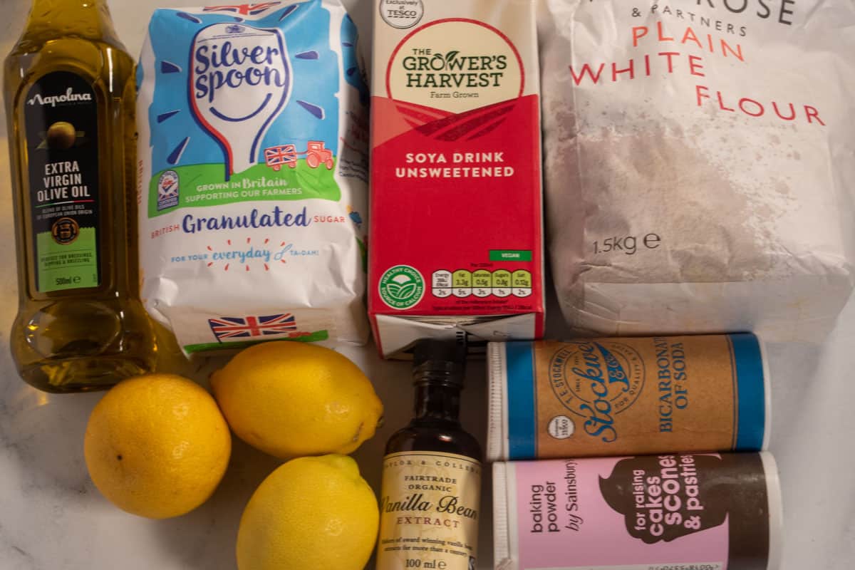 The ingredients needed to make my vegan lemon olive oil cake laid out over a white, marble background.