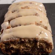 A whole loaf of my vegan maple pecan cake sliced equally. It is covered with maple glaze.