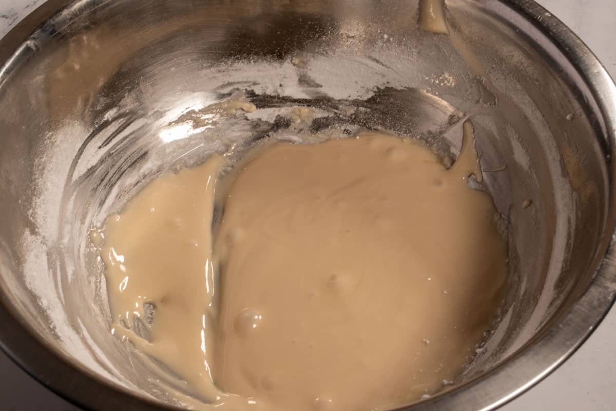 The maple glaze inside a metal mixing bowl, waiting to be spooned onto the cakes.