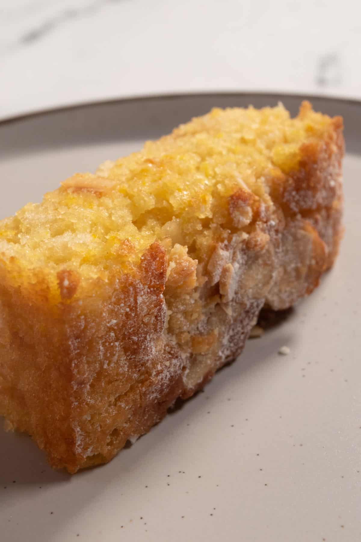 A thick slice of orange cake on a brown-rimmed serving plate. The crumb of the cake is very moist.