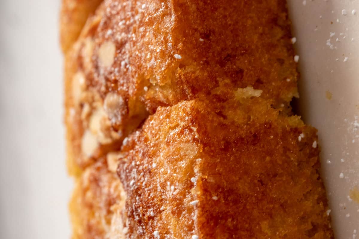 The baked cake is golden brown and is sprinkled with powdered sugar. 