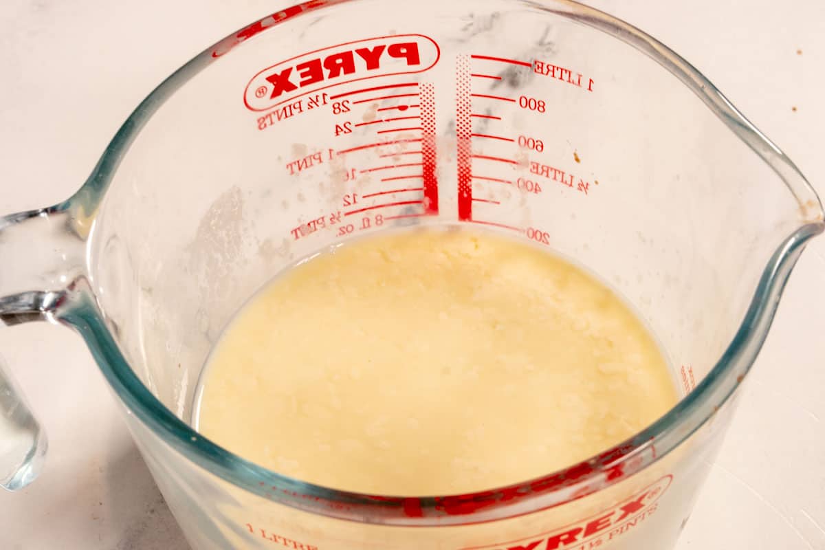 The vegan buttermilk curdling inside a glass measuring jug. 