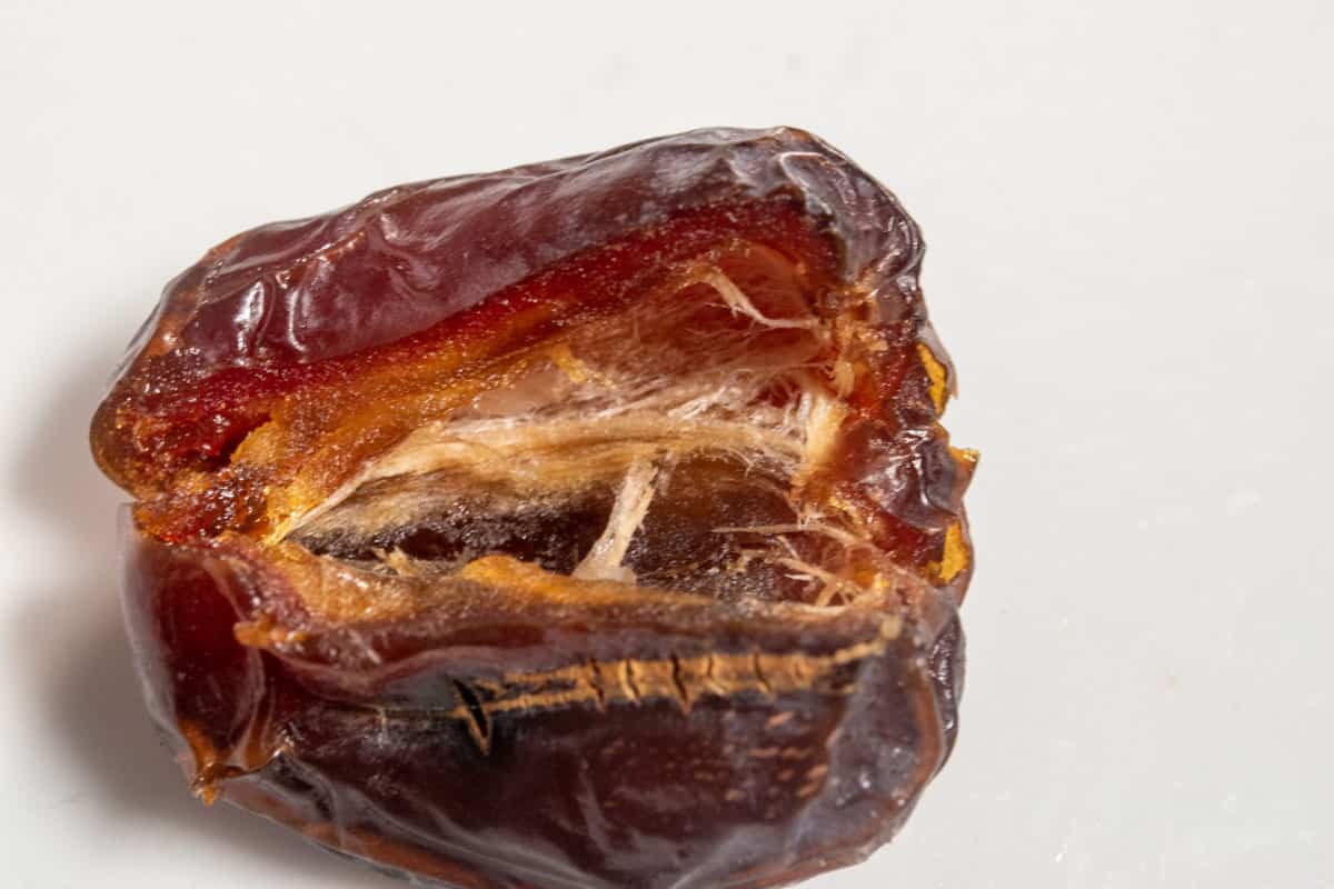 A single date sliced and opened up revealing all its insides. 