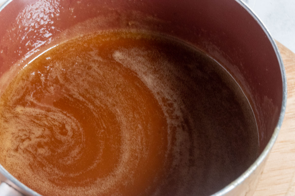 The toffee sauce cooking inside a saucepan. 