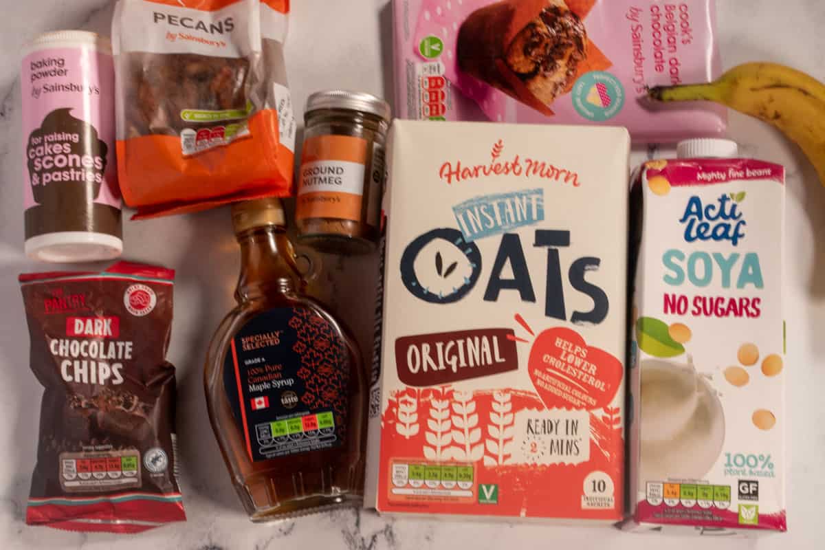 The ingredients need to make vegan banana bread baked oats, laid out over a white marble background.