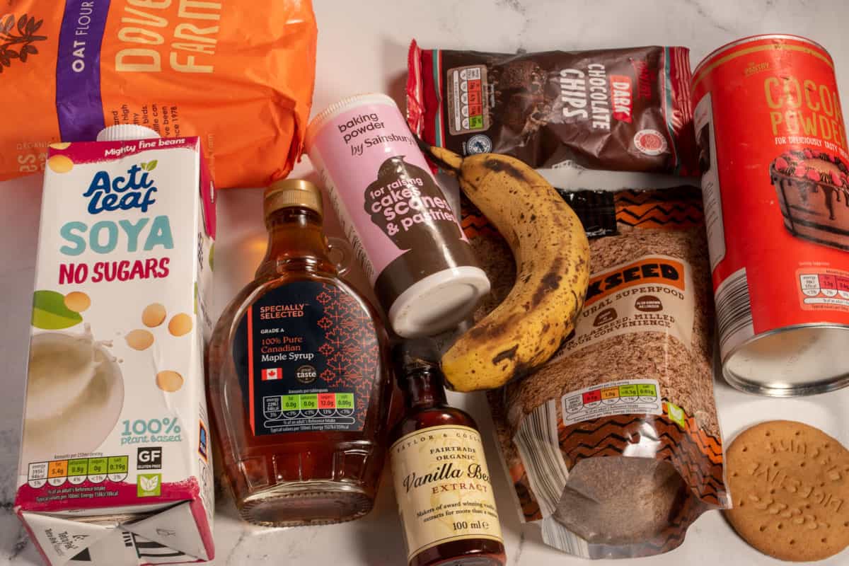 The ingredients that you will need to make chocolate baked oatmeal laid out over a white, marble background.