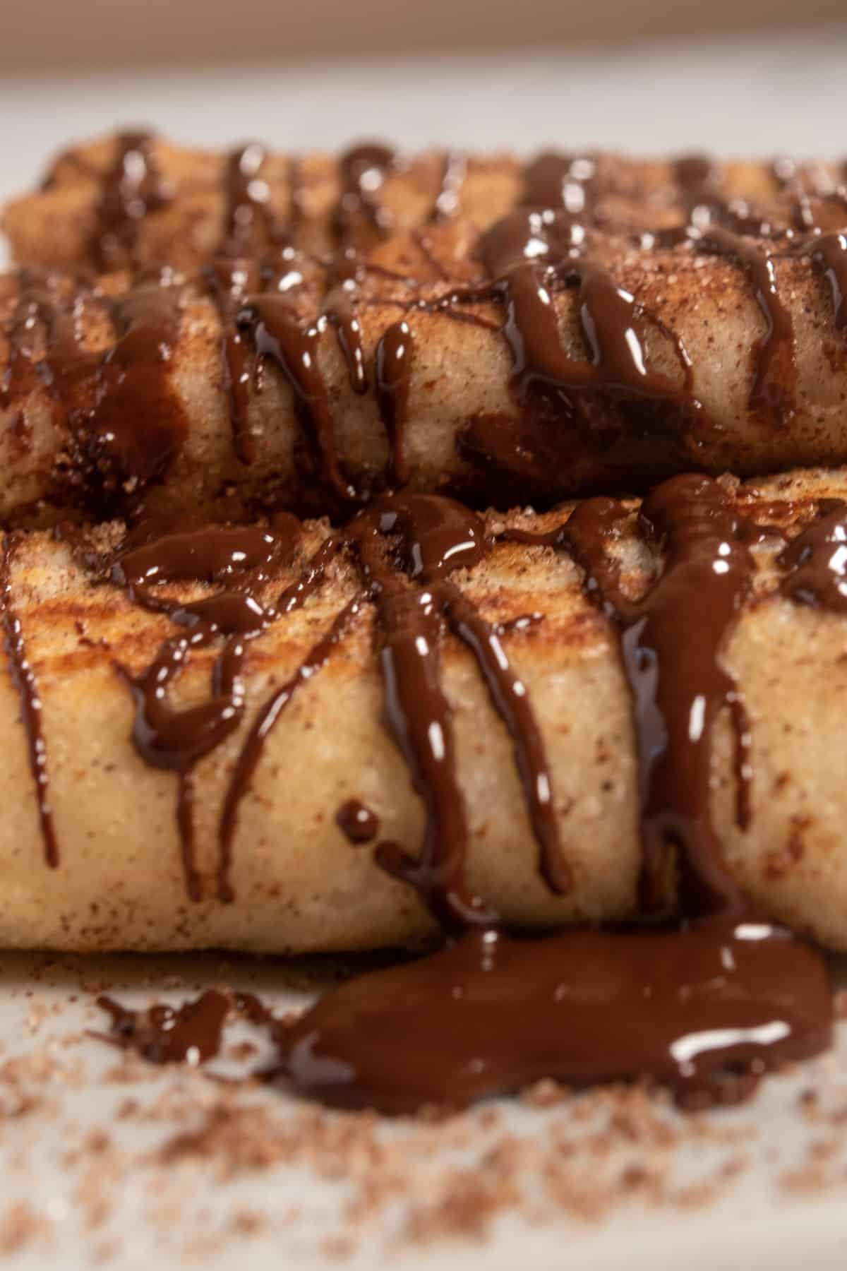 A large pile of chocolatey rolls cooling down waiting to be eaten. They're dusted with plenty of cinnamon.