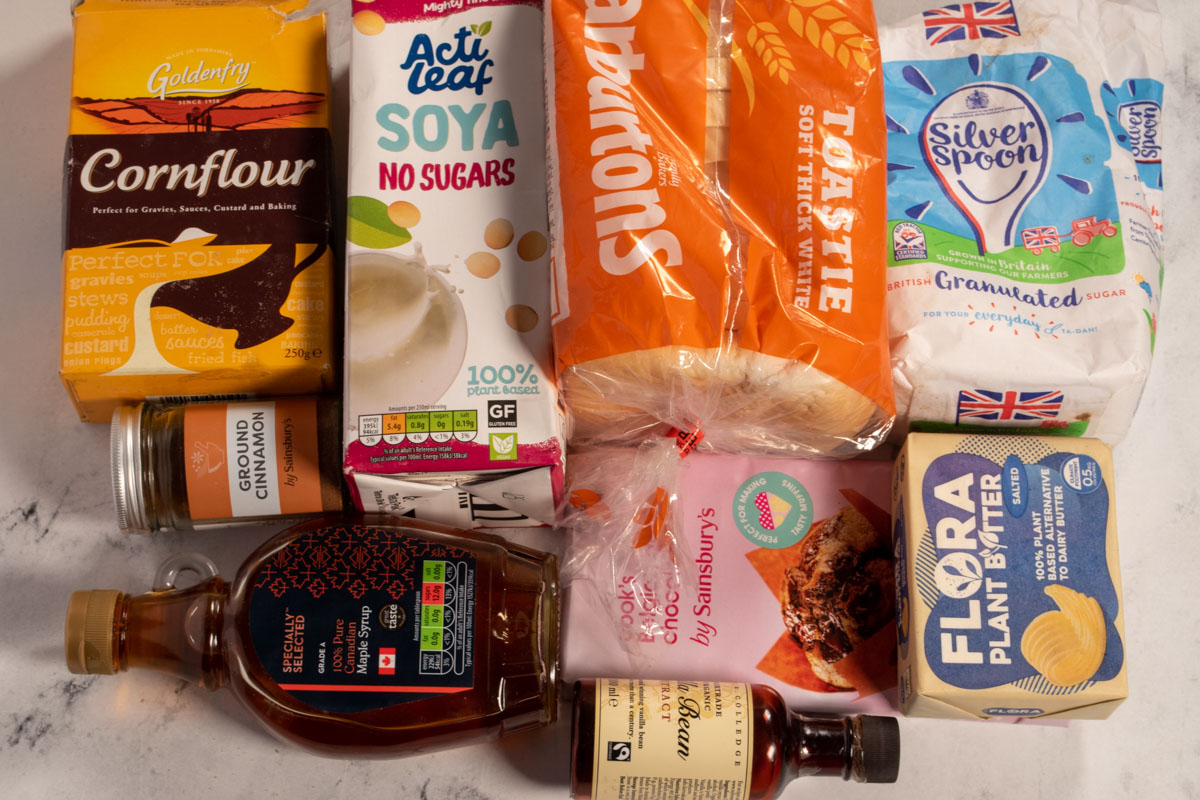 The recipe ingredients you need to make chocolate french toast rolls laid out neatly over a white, marble background.