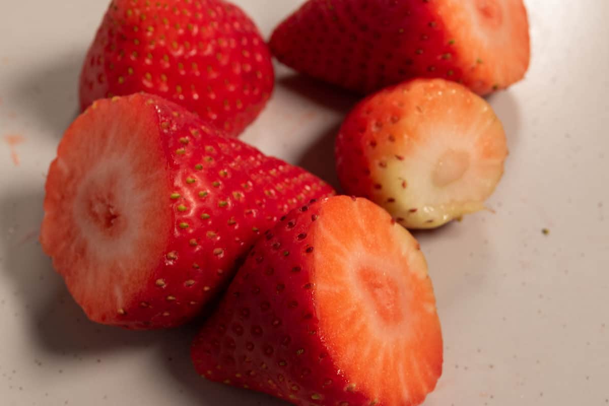 A collection of strawberries with the tops sliced off. 