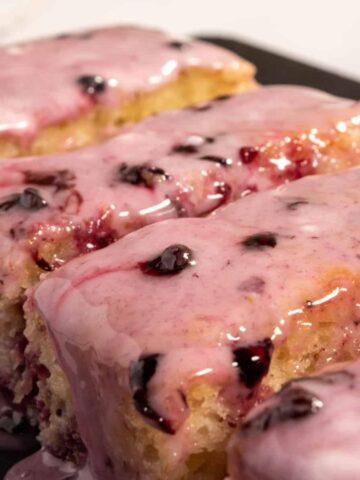 An angled photo of a whole vegan blackberry cake loaf which is sliced and moist.