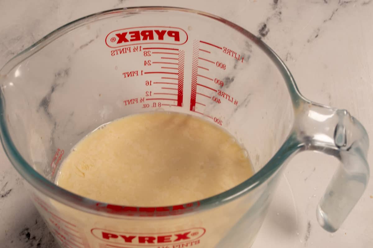 A photo of vegan buttermilk curdling inside a large jug. 